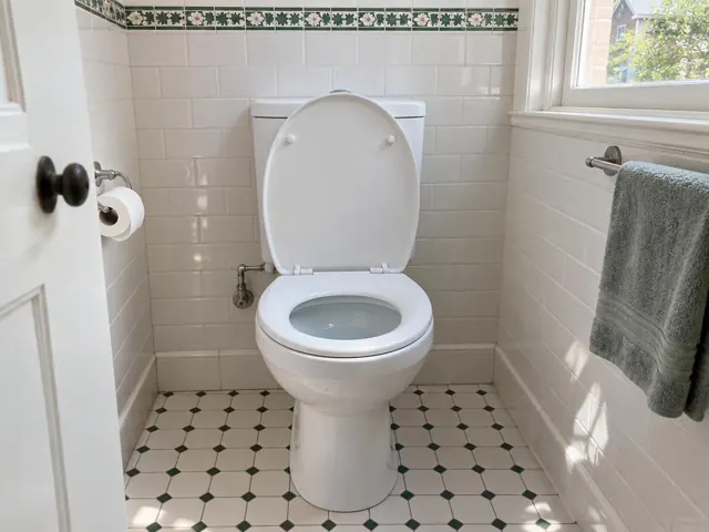 Clean white toilet in a tiled bathroom with patterned floor and towel rail in Penshurst